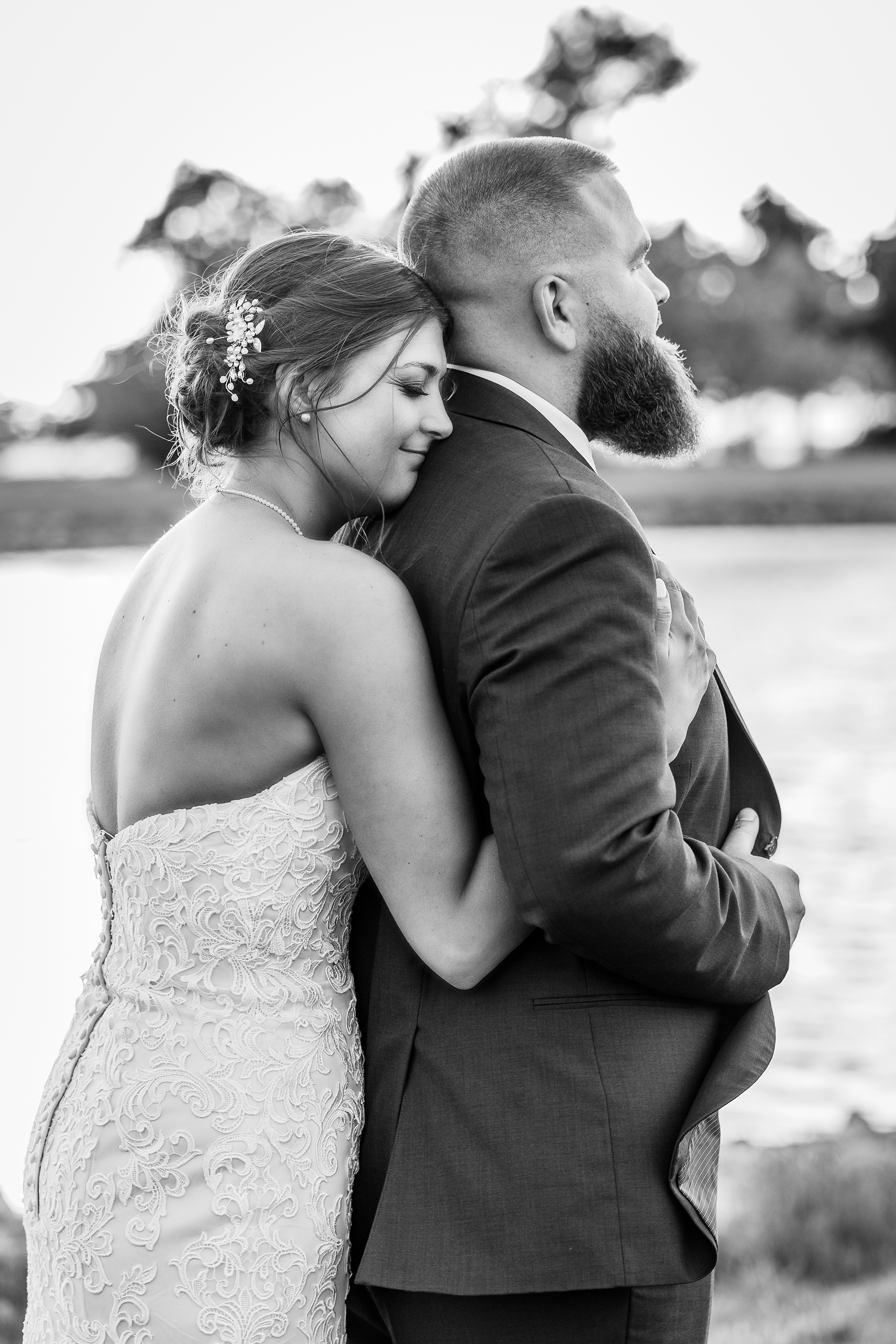 black and white portrait of bride hugging groom from behind