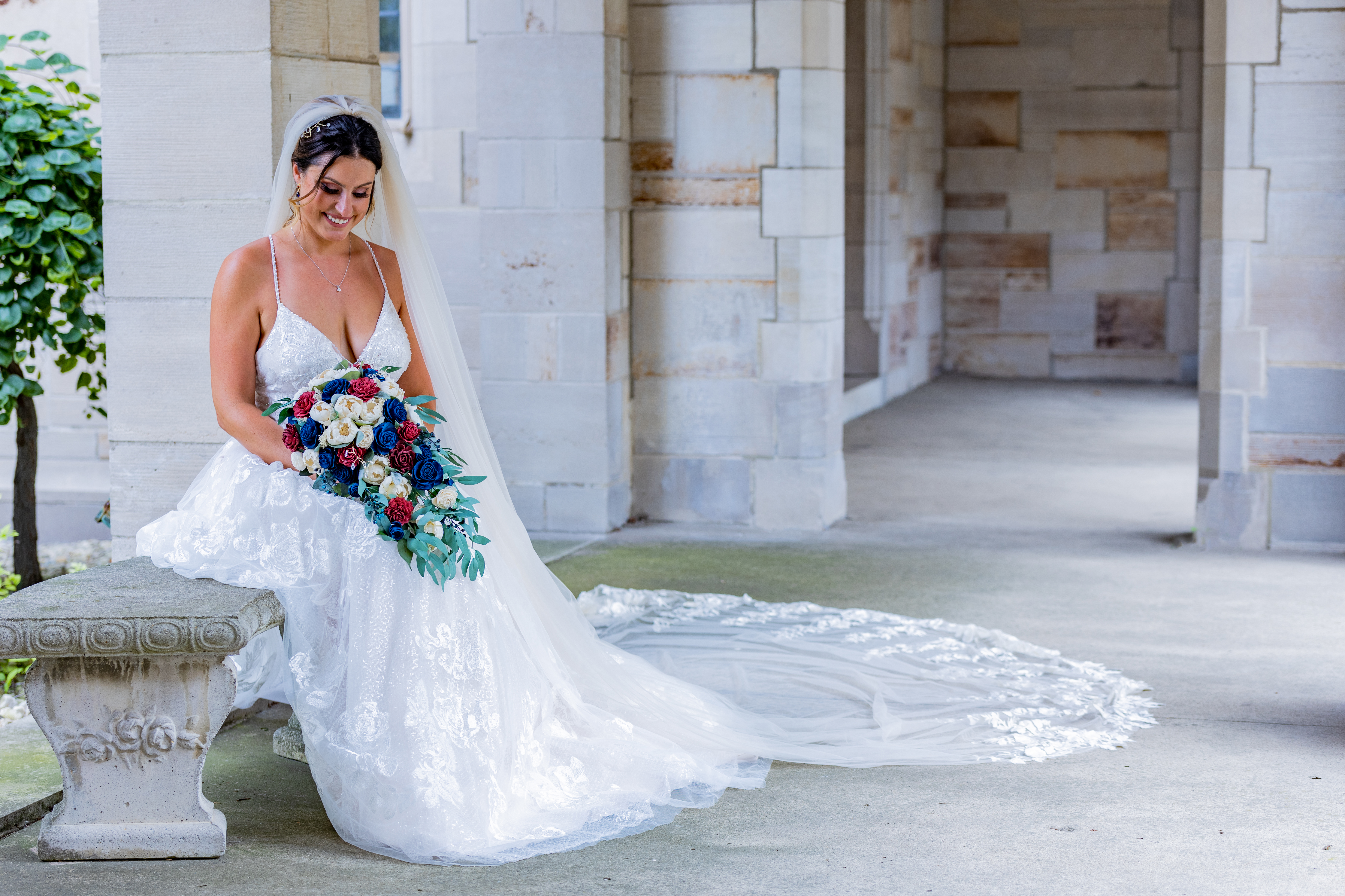 bride sitting on bench with veil surrounding her