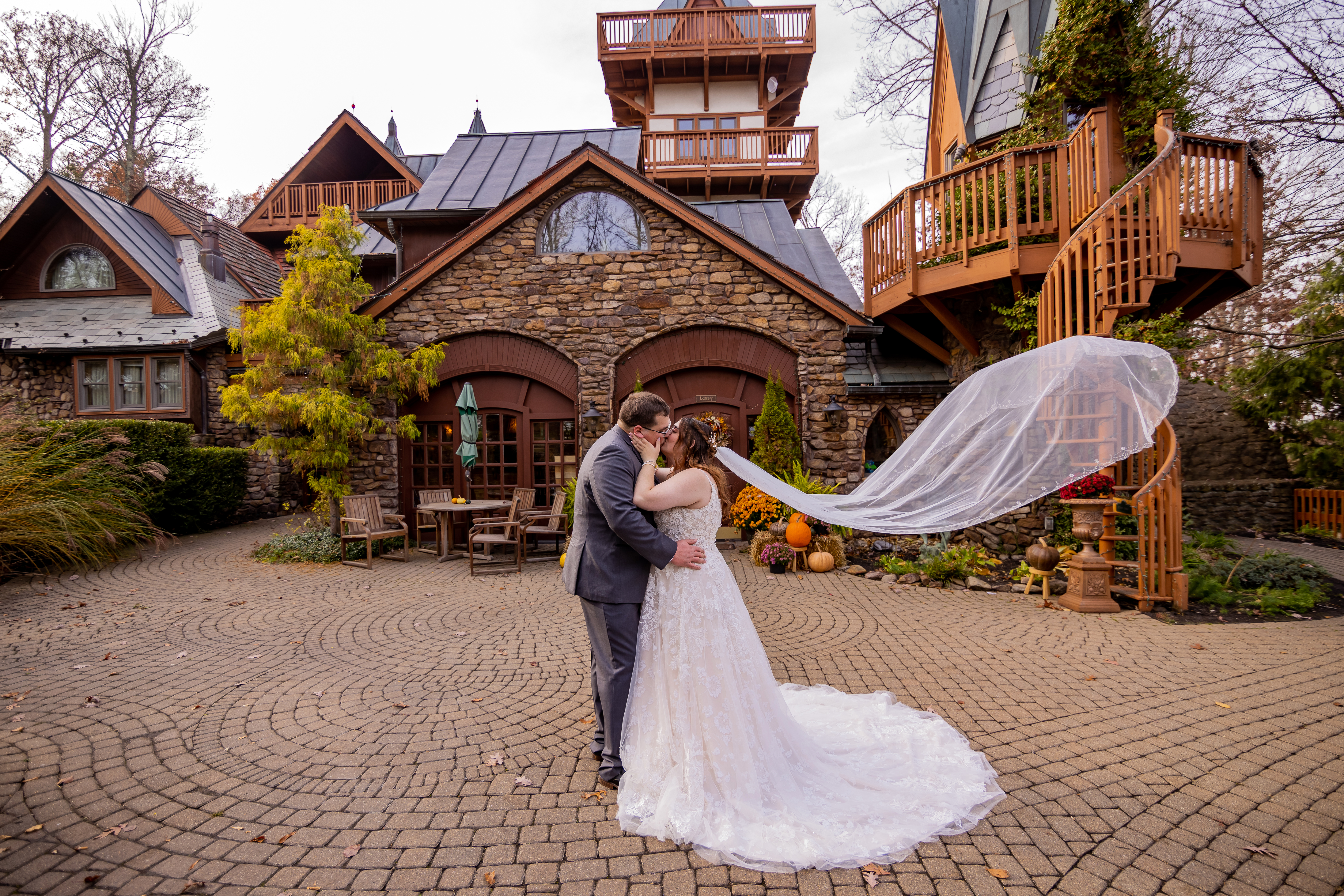 couple kissing while bride's veil flows behind her