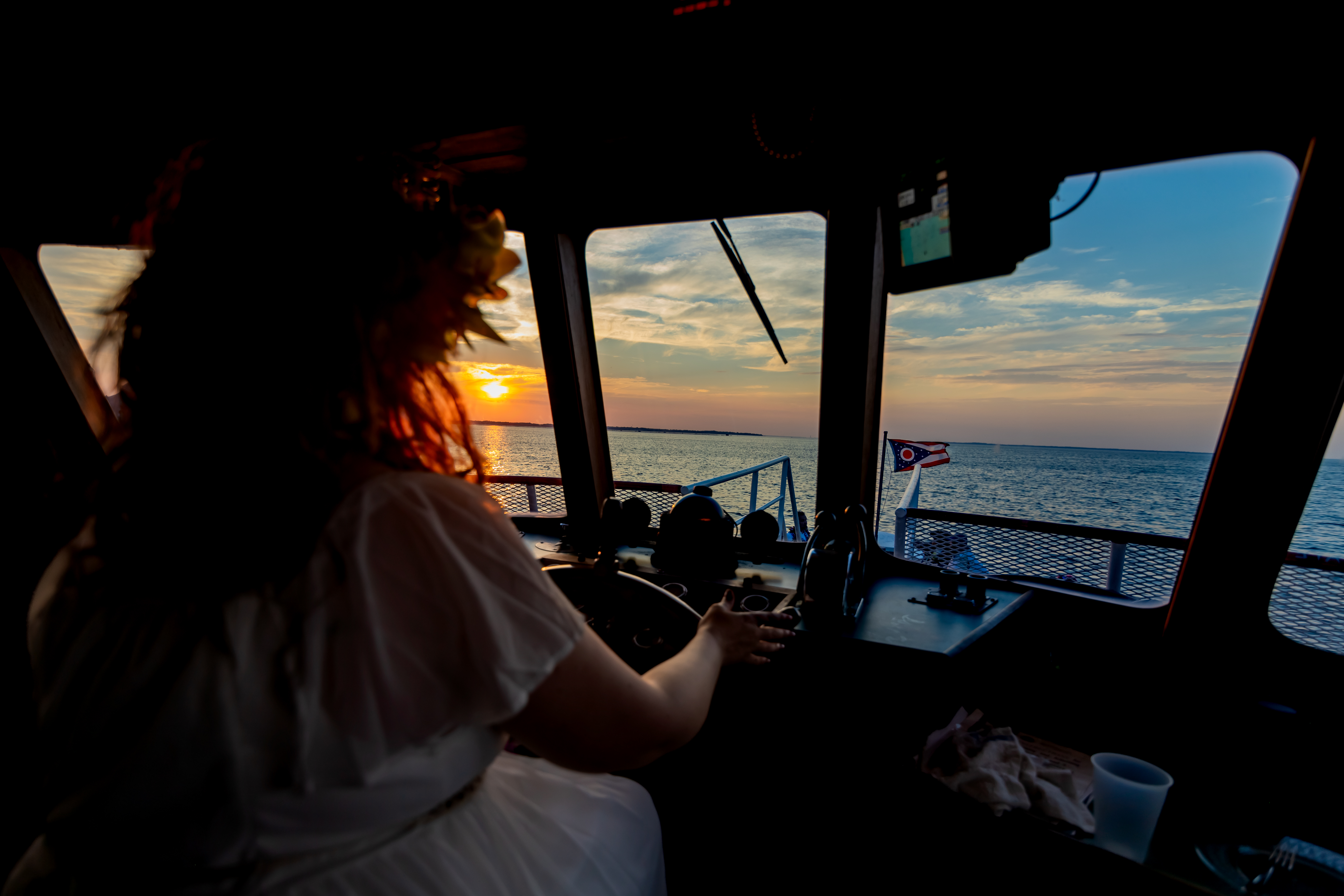 bride steering boat at sunset