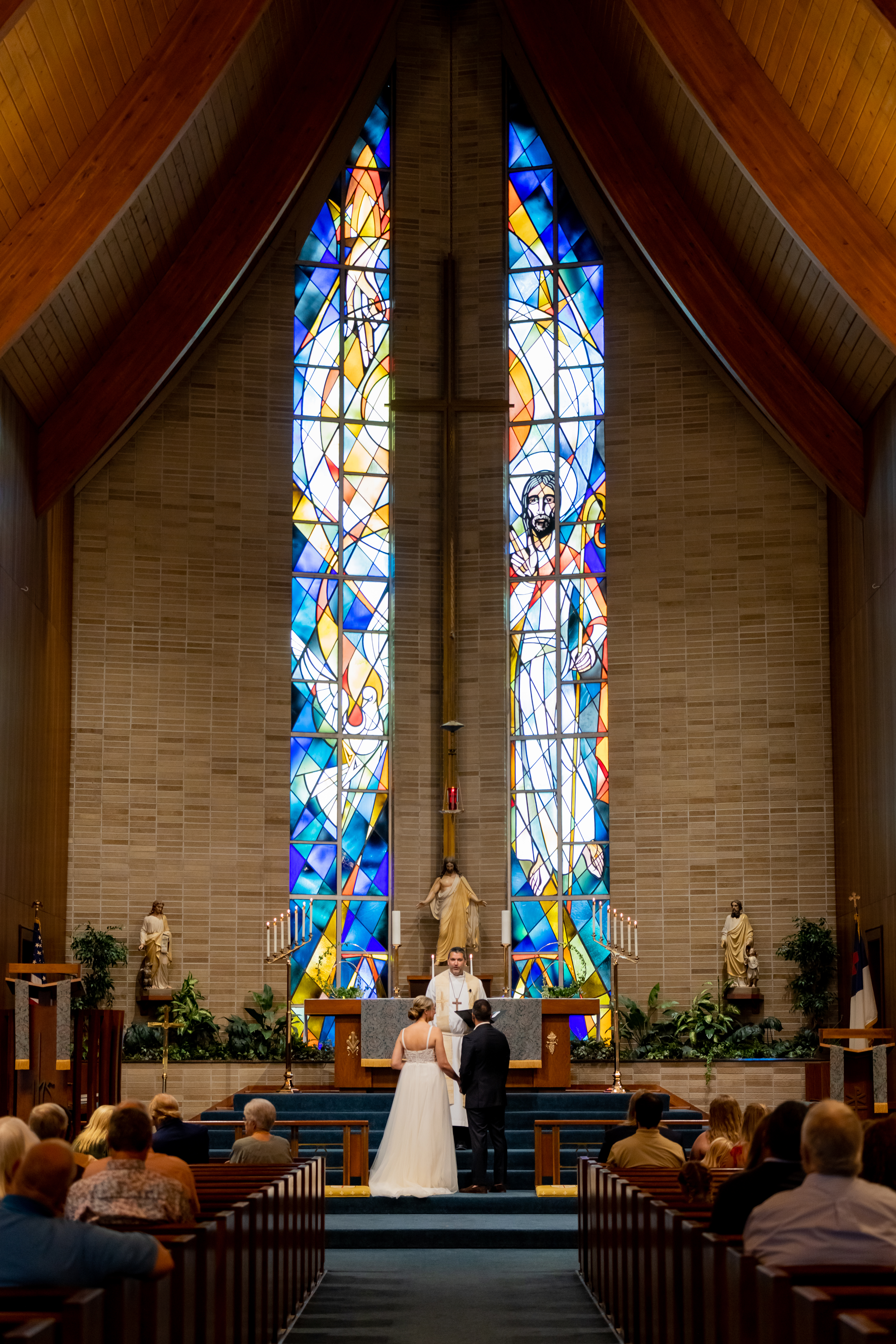 couple at altar in church wedding with large stained glass window