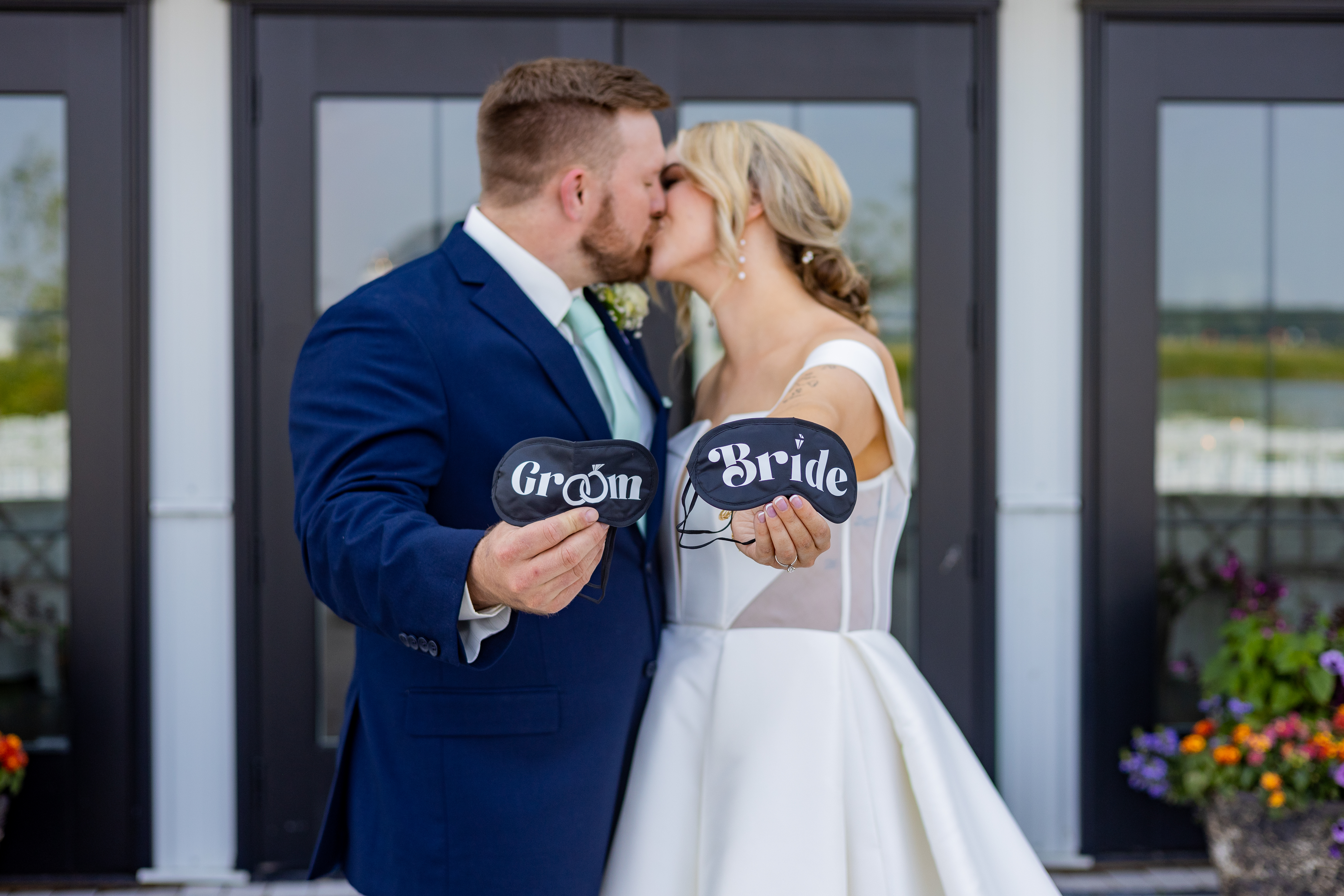bride and groom kissing holding eye masks