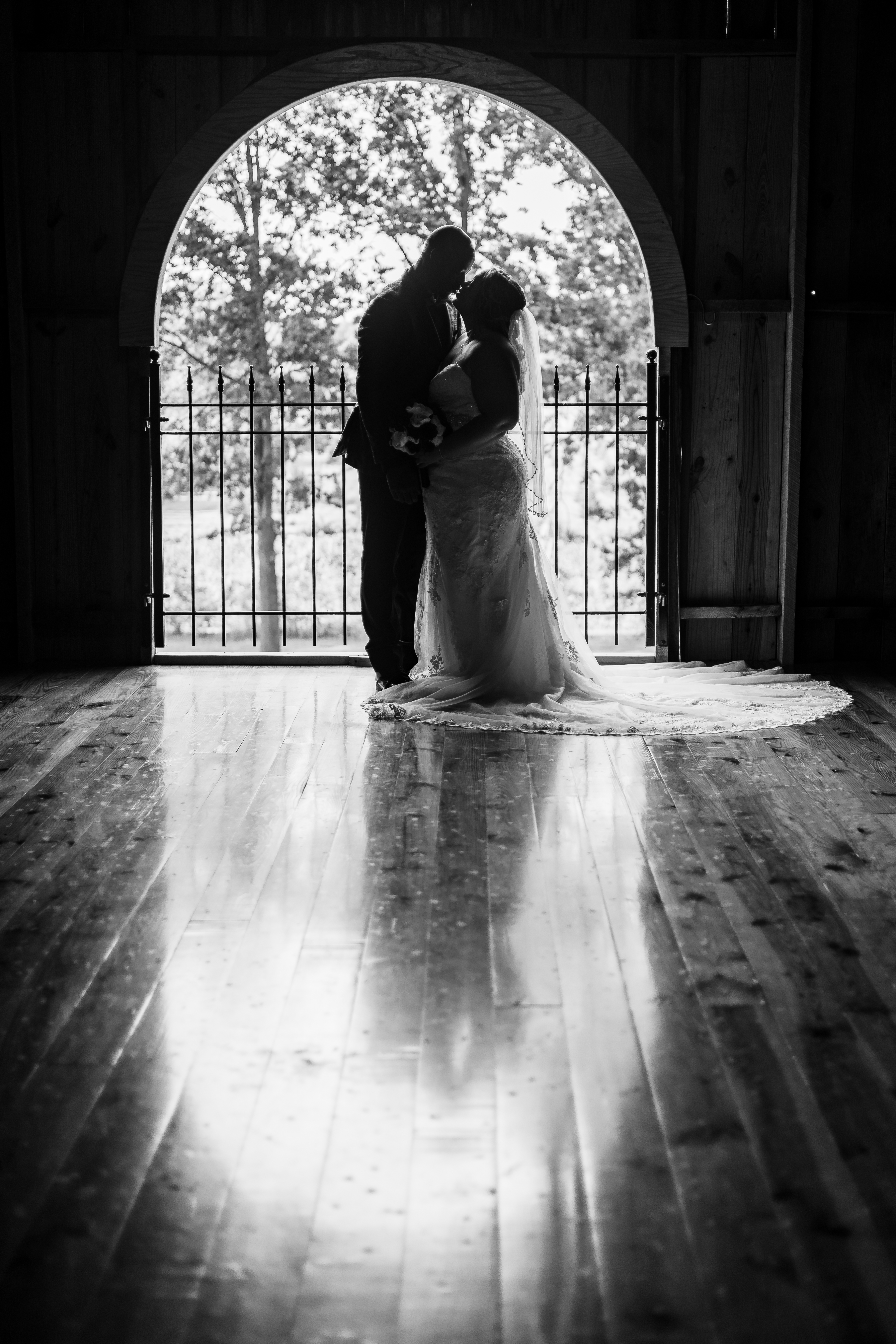 black and white portrait of couple kissing under arched window