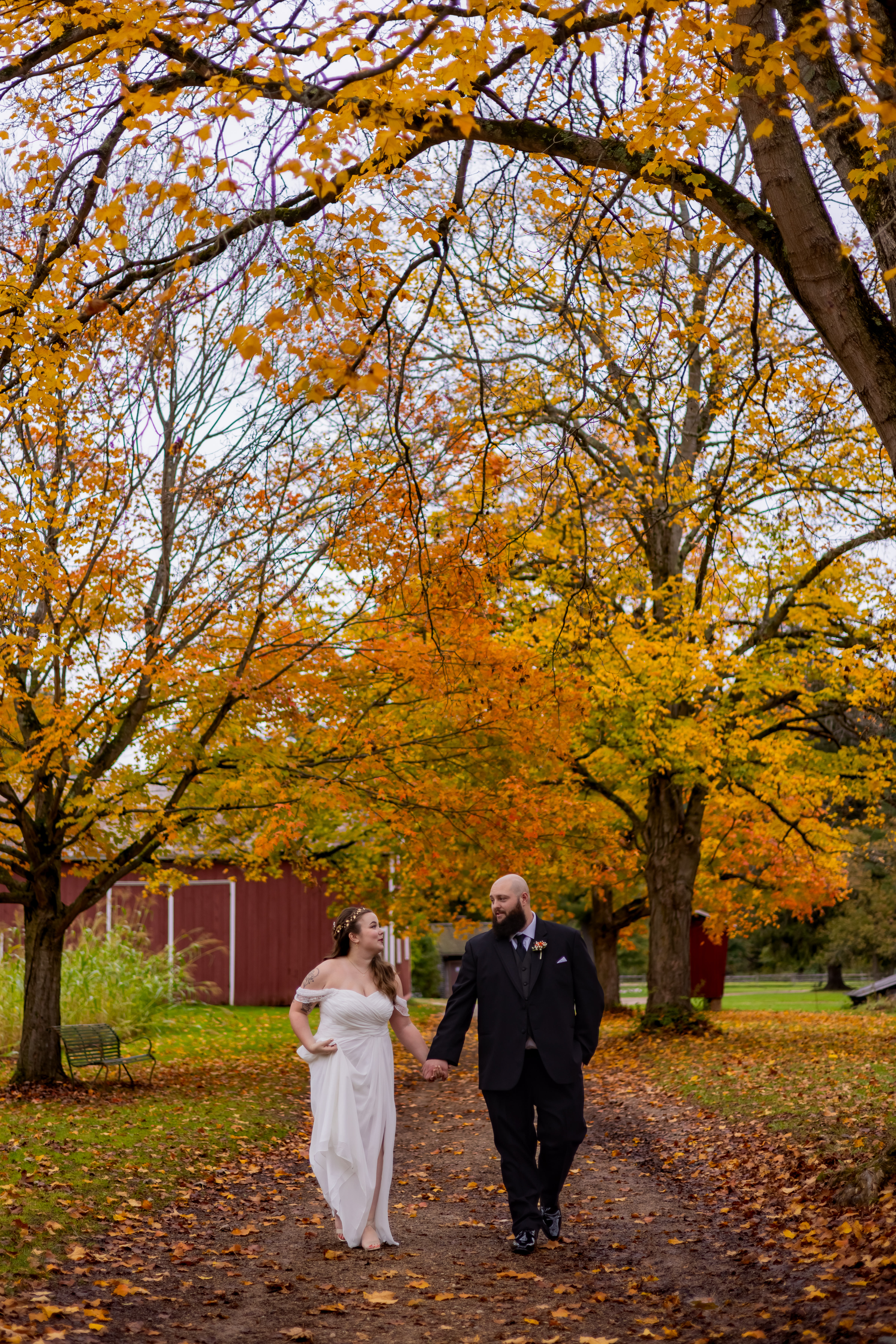 bride and groom holding hands under fall trees
