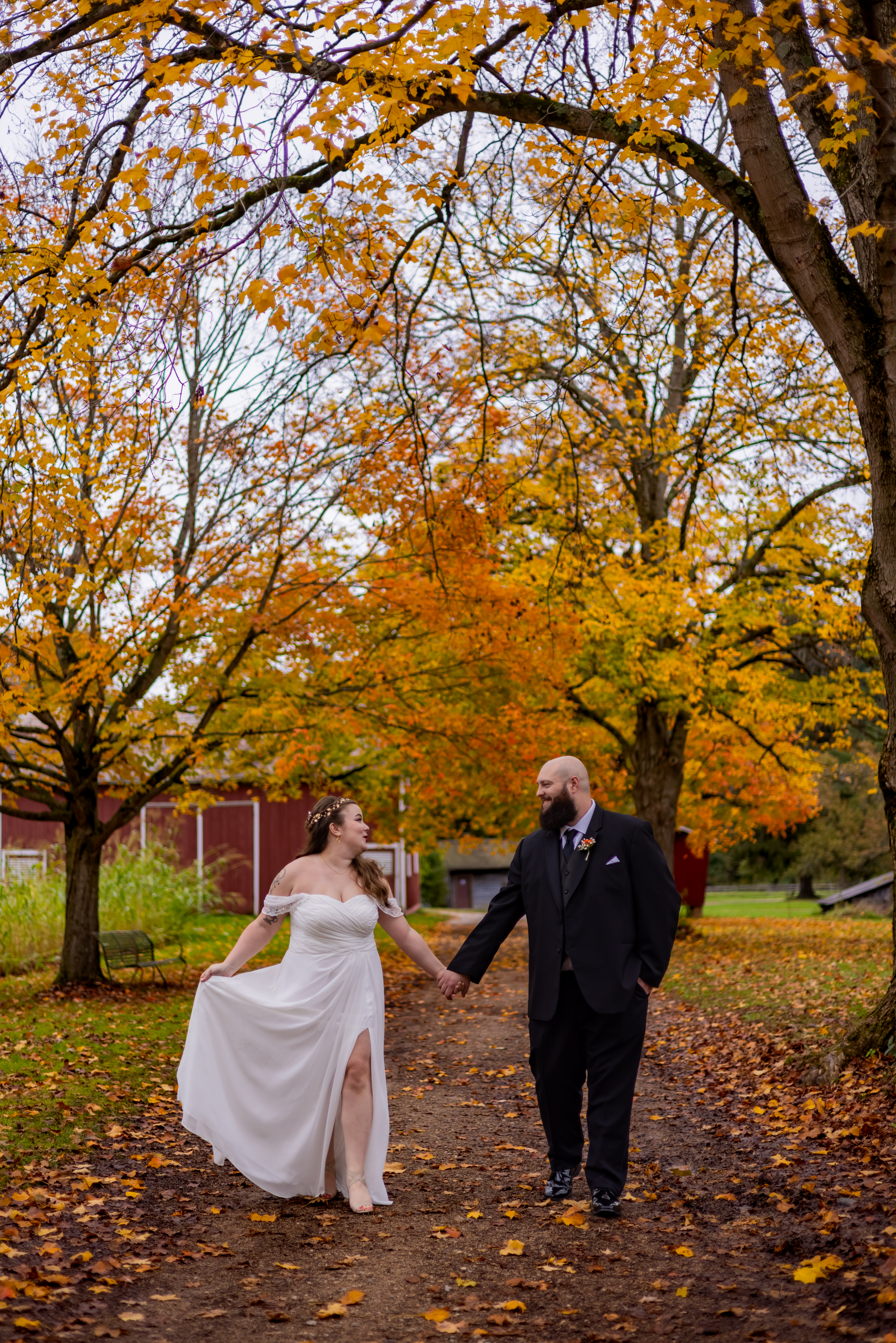 bride and groom walking under fall colored trees