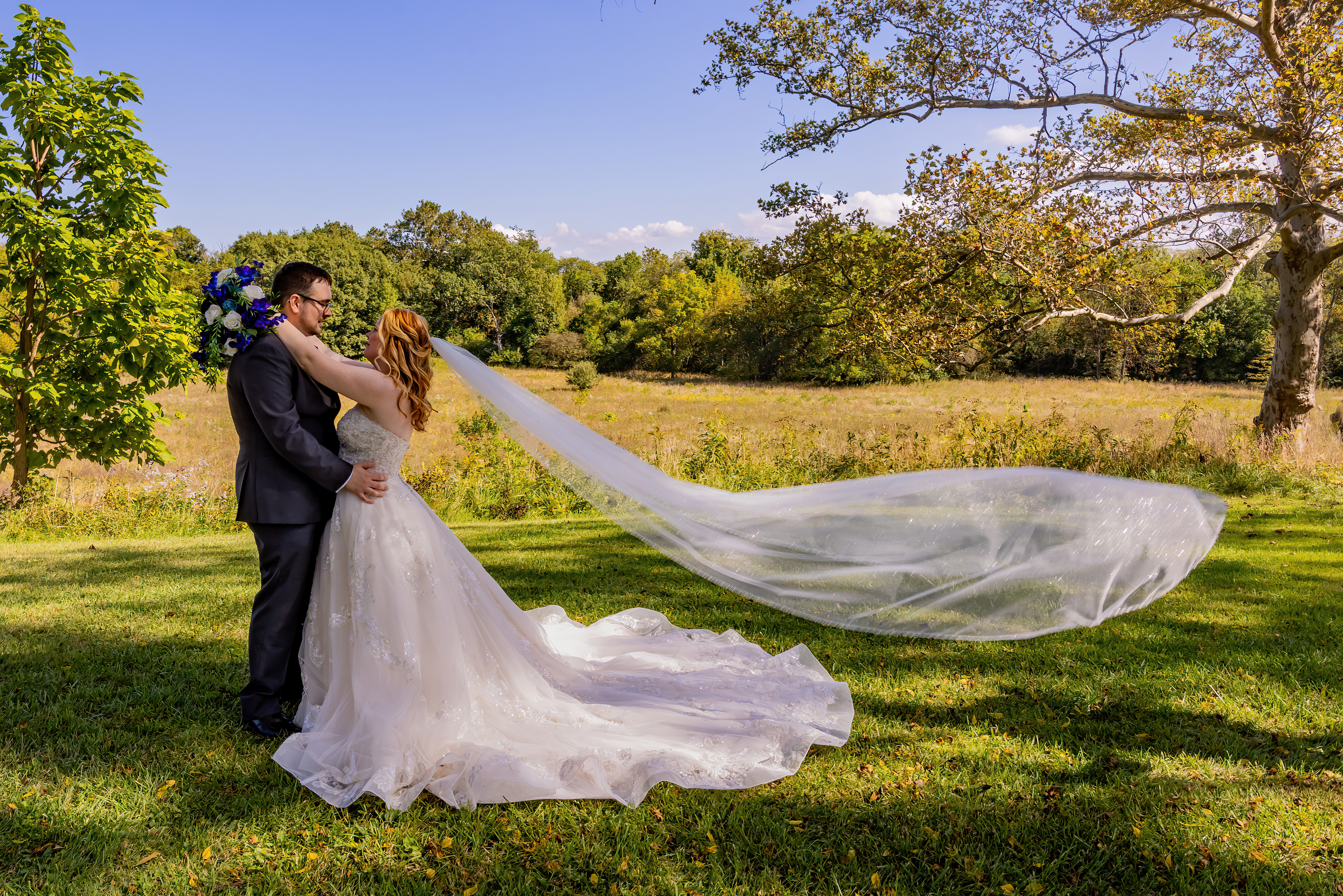 bride and groom embracing in green field