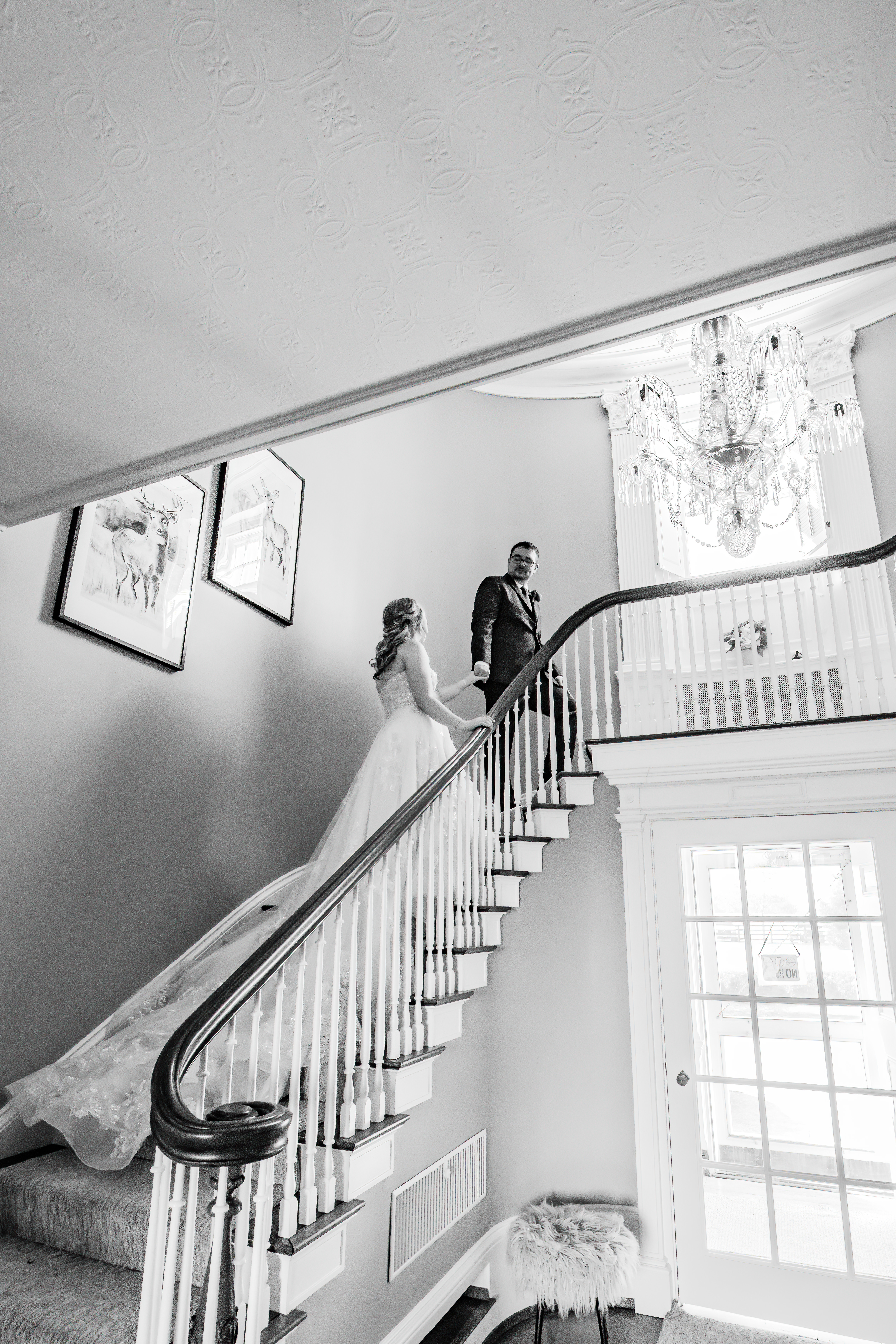 black and white portrait of bride and groom walking up stairs holding hands