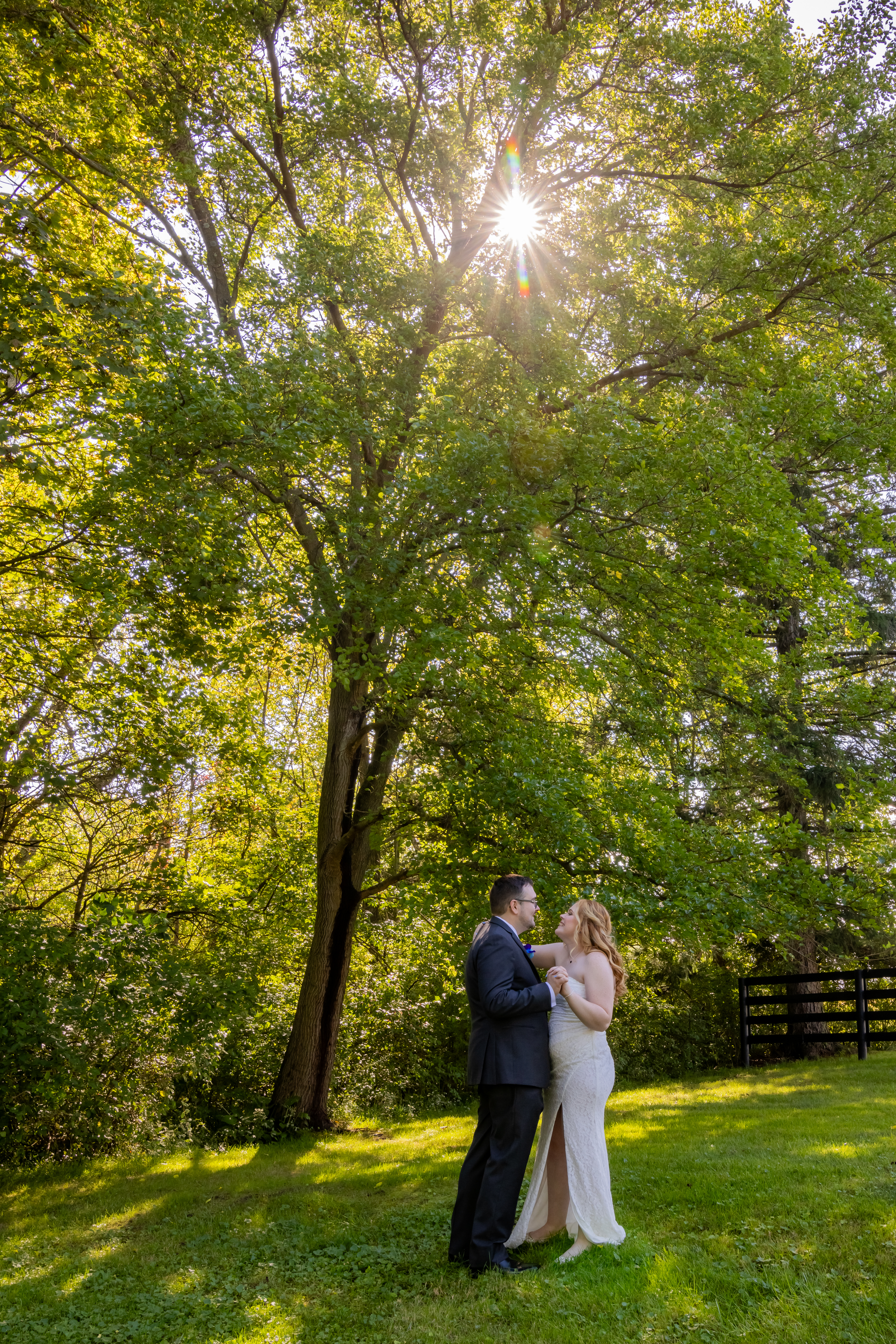 bride and groom under green summer trees