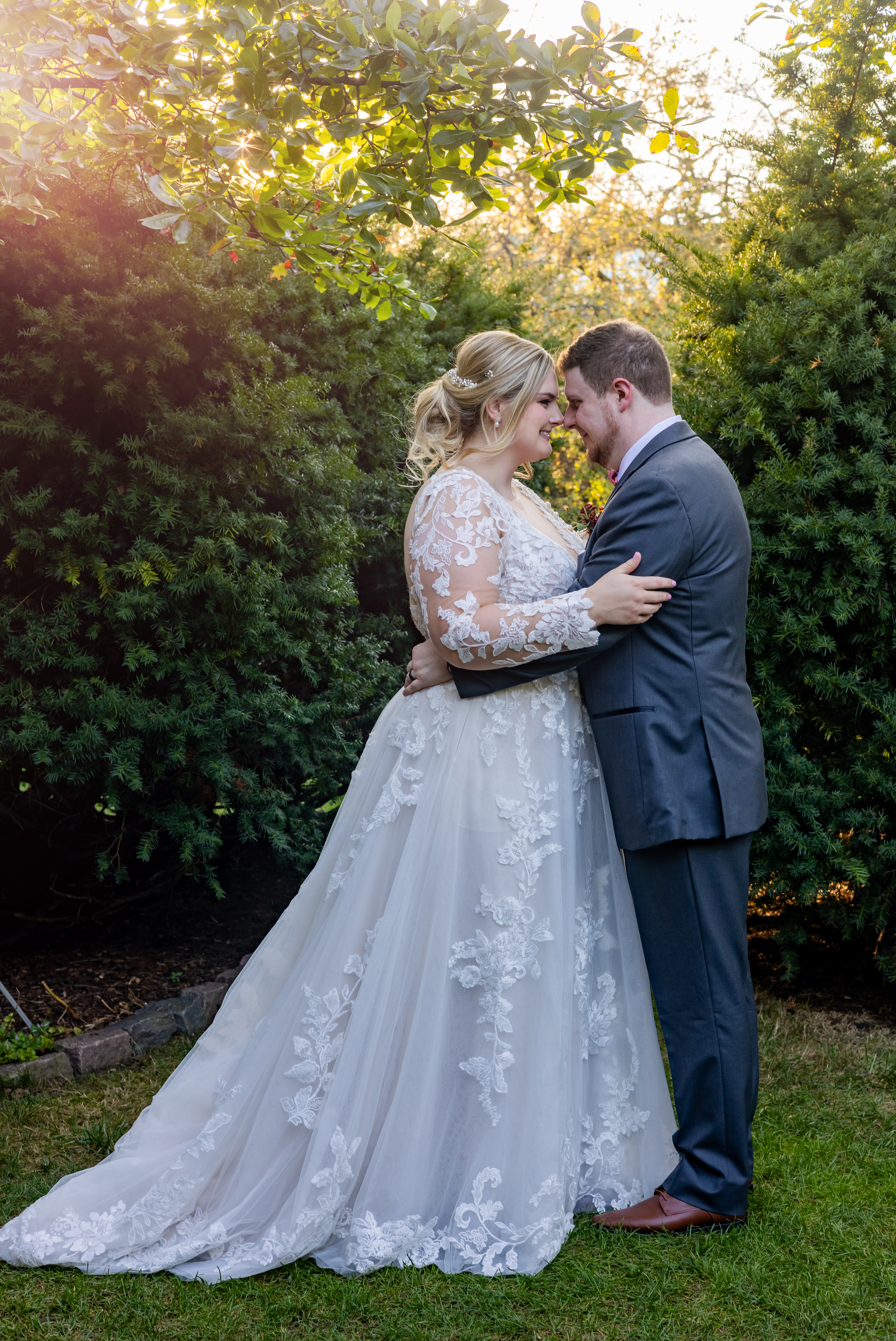 couple embracing in front of green trees