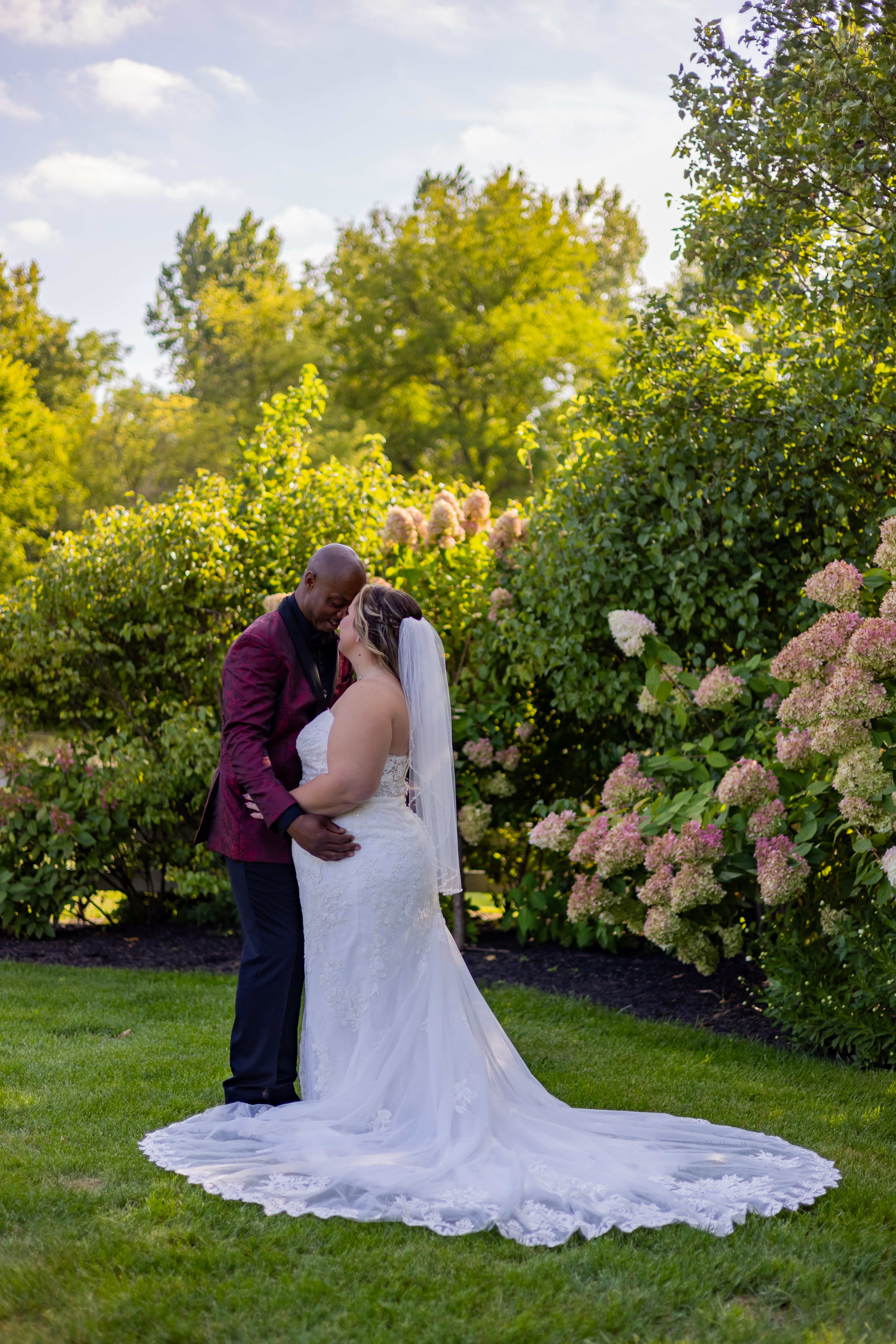 couple embracing in front of hydrangea bushes