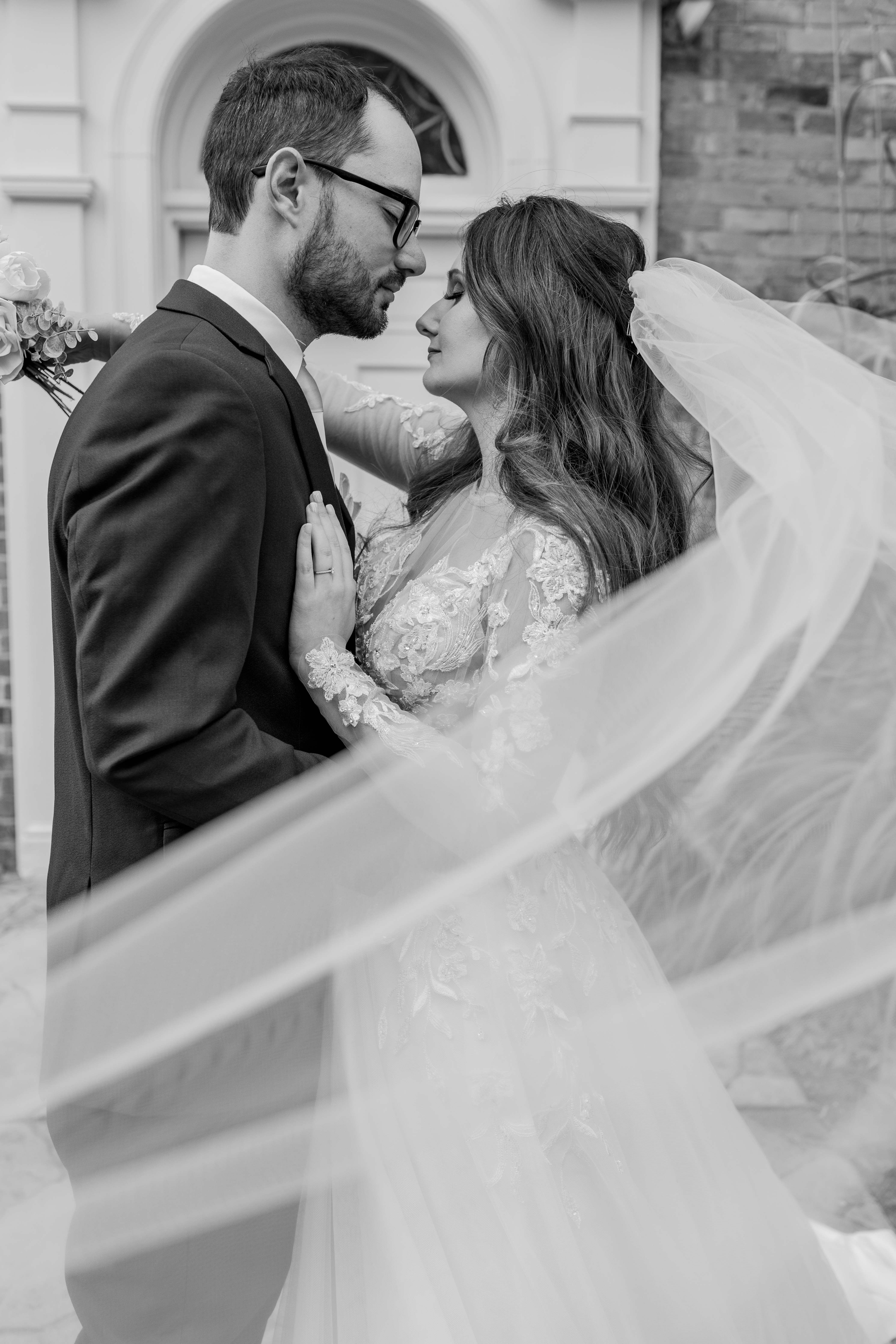 black and white portrait of bride and groom surrounded by bride's veil