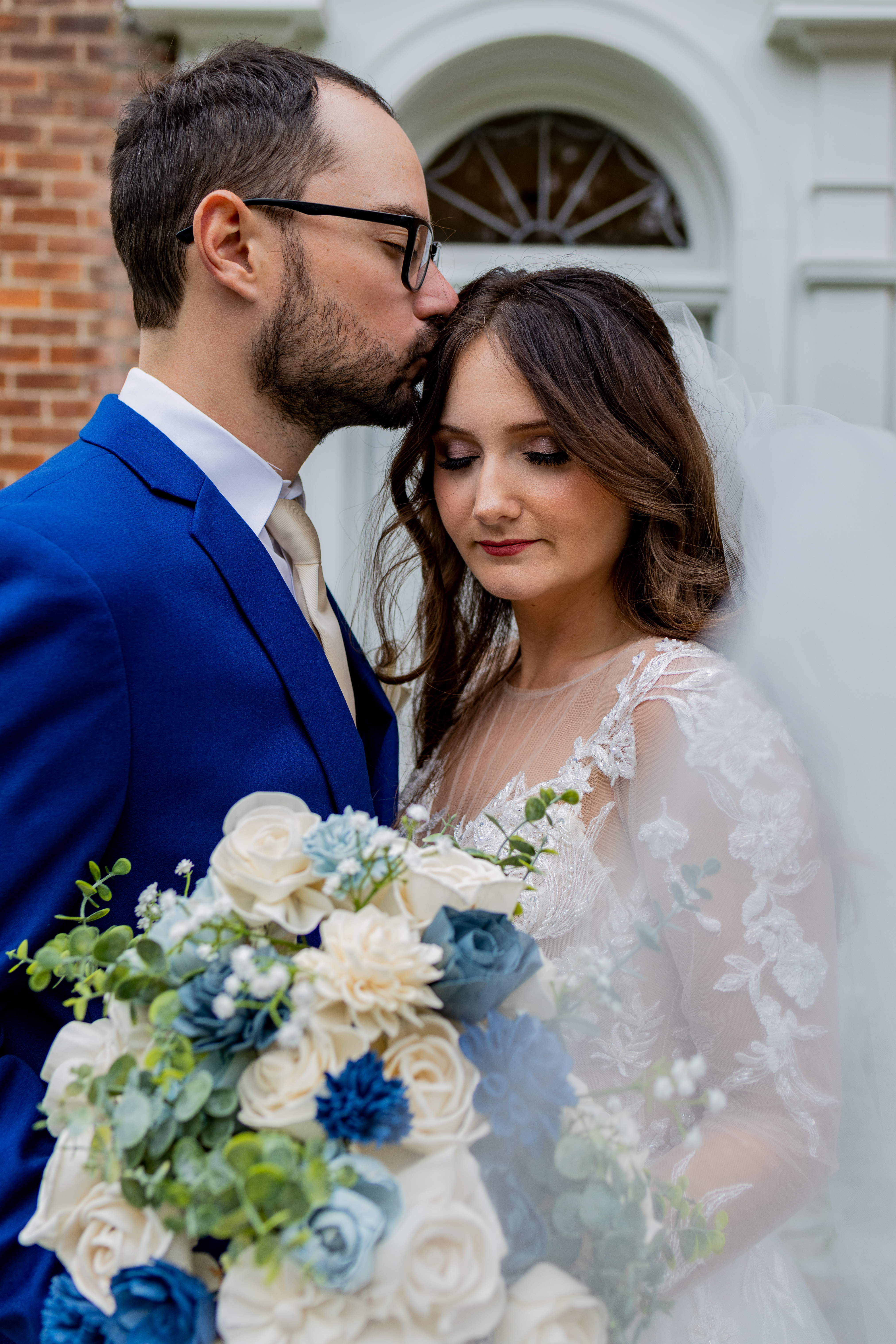 groom kissing bride on head
