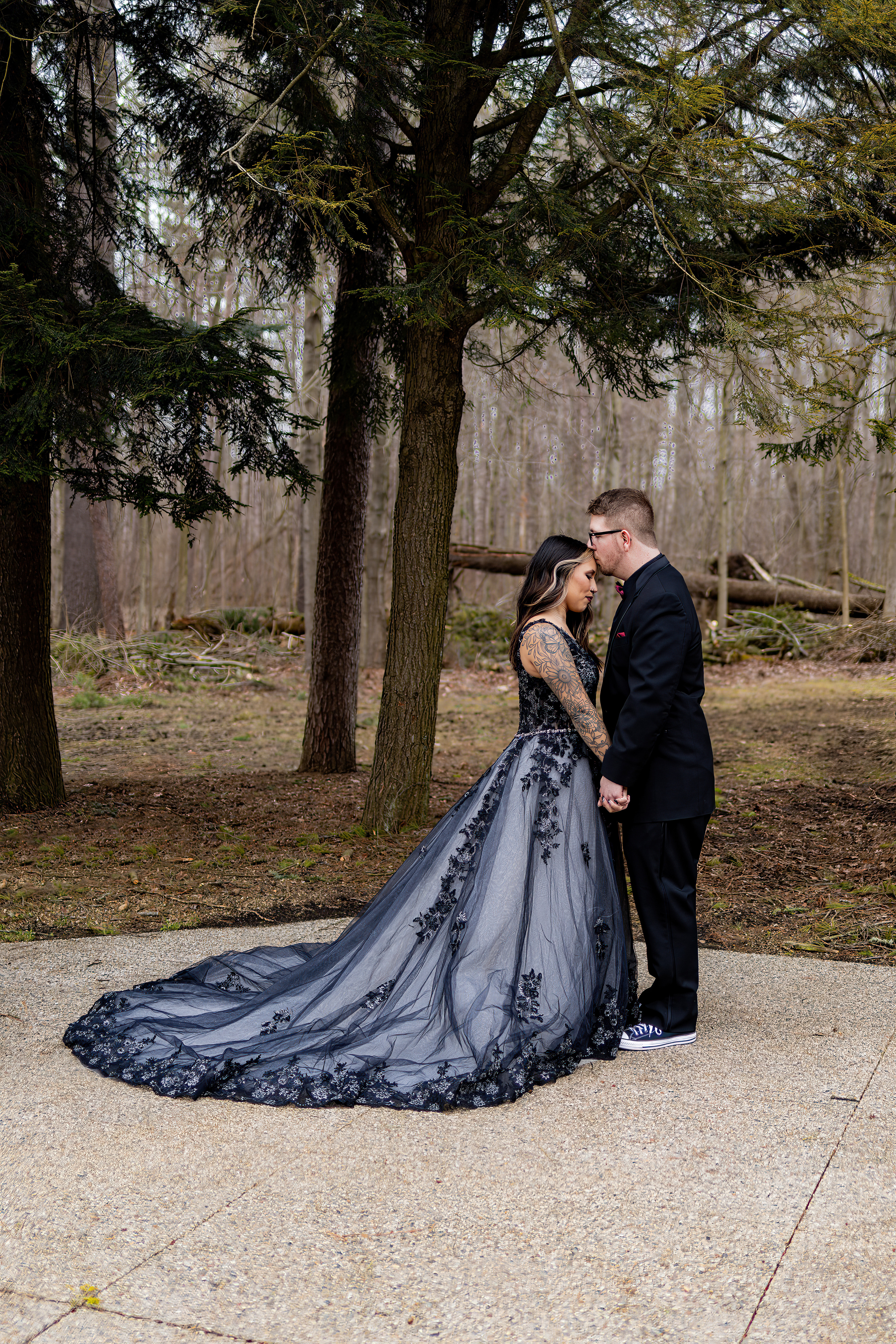 portrait of groom kissing bride on forehead wearing black lace gown