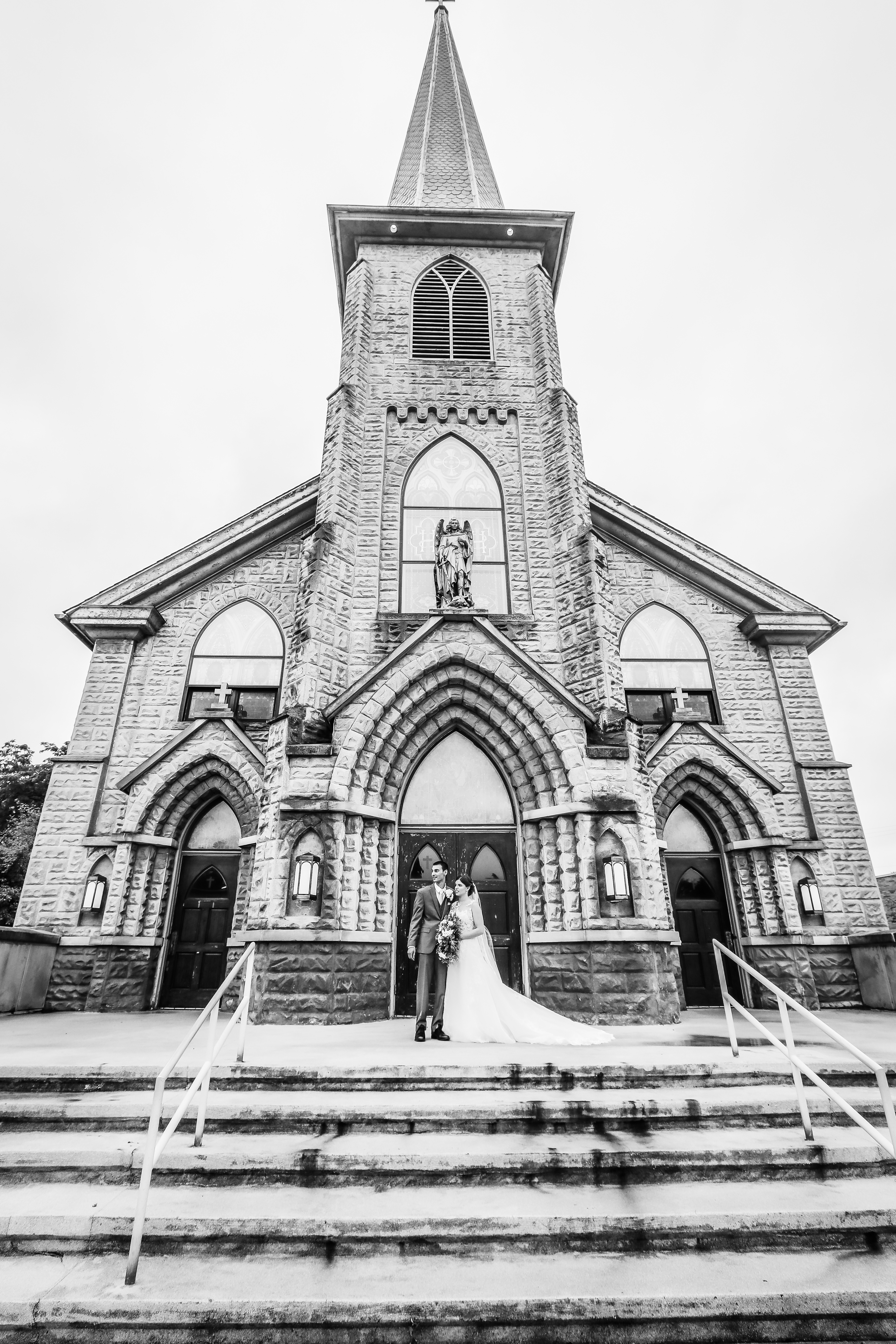 black and white wedding portrait of couple on historic church steps