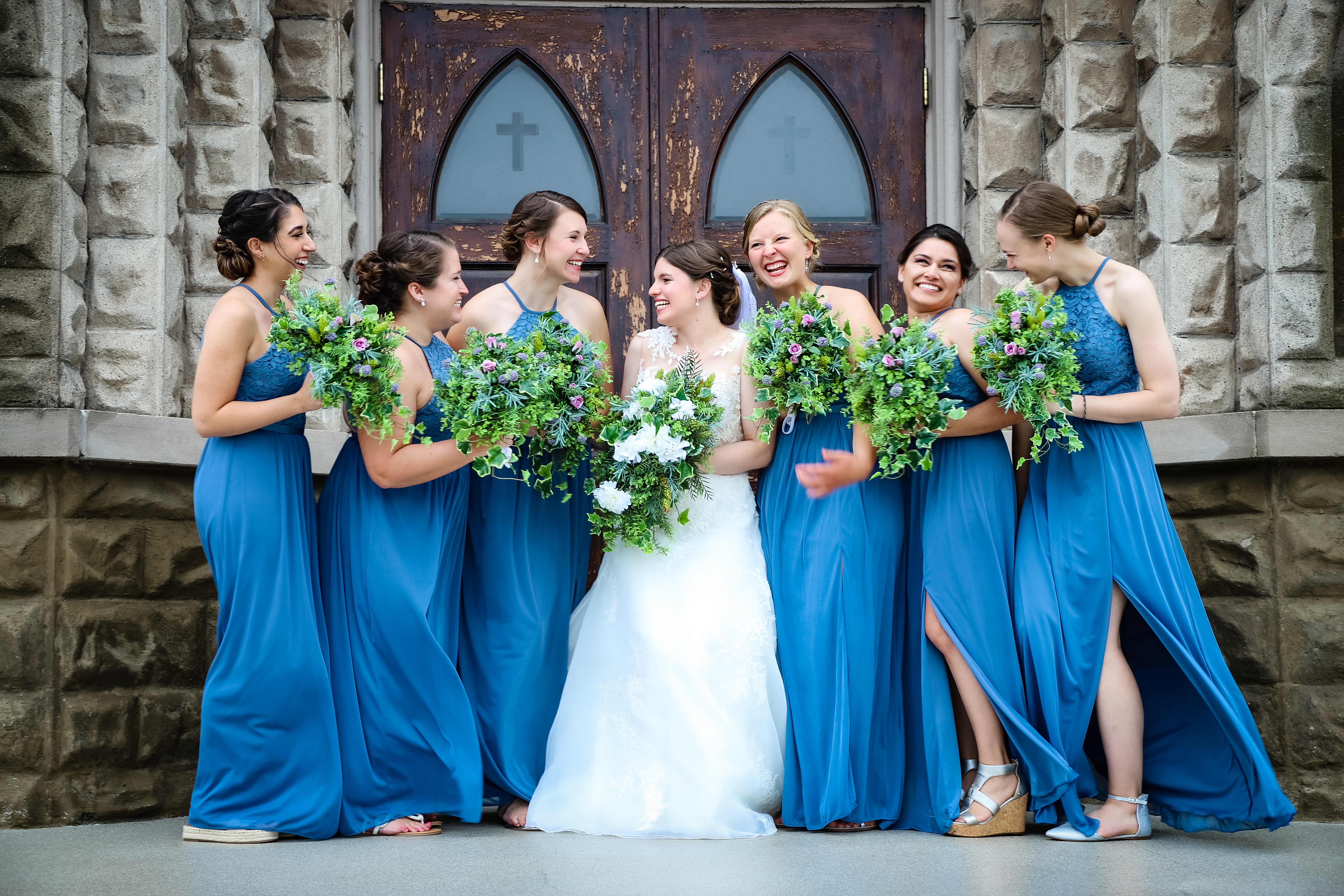 bride and bridesmaids laughing on church steps