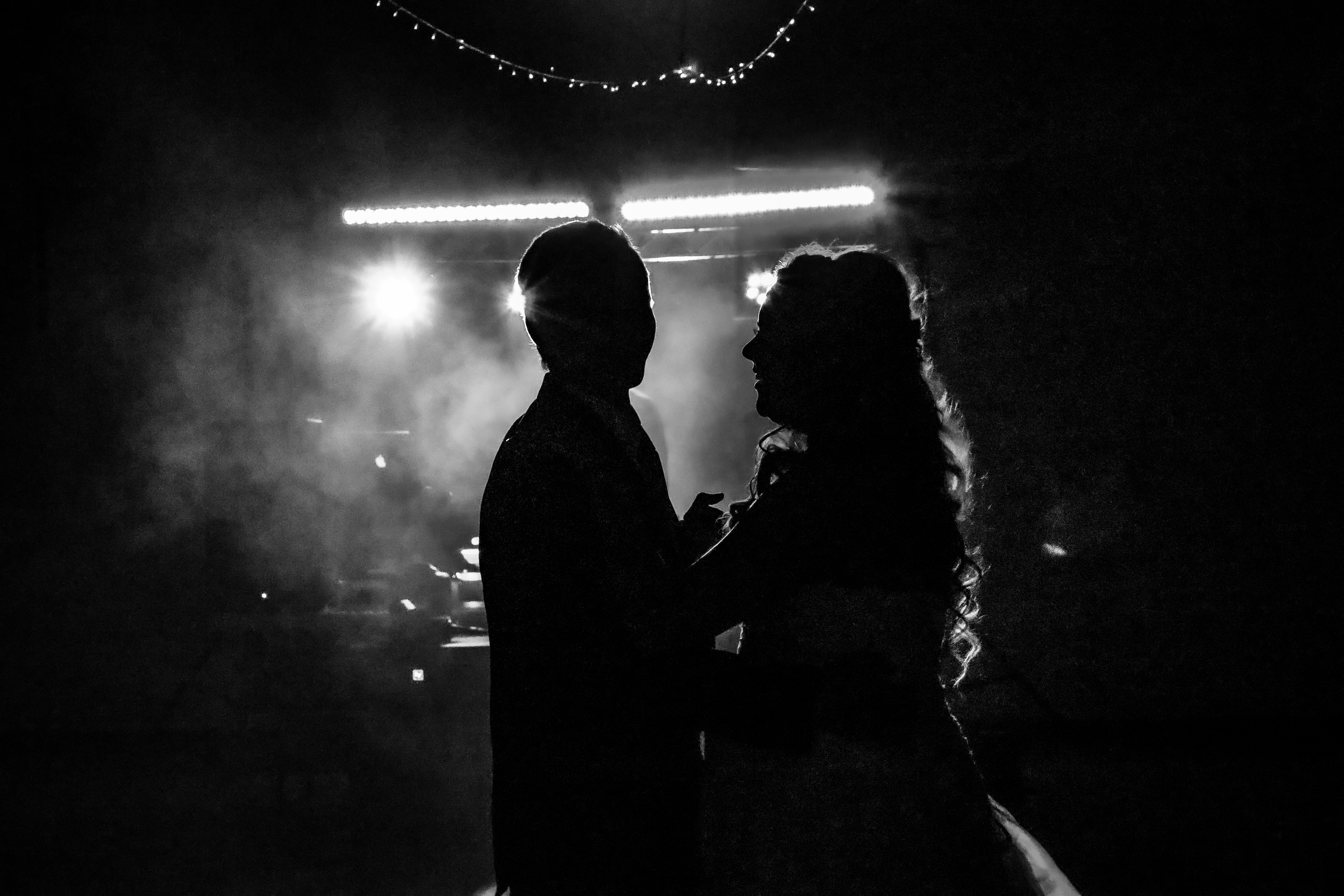 black and white portrait of bride and groom under dancefloor lights