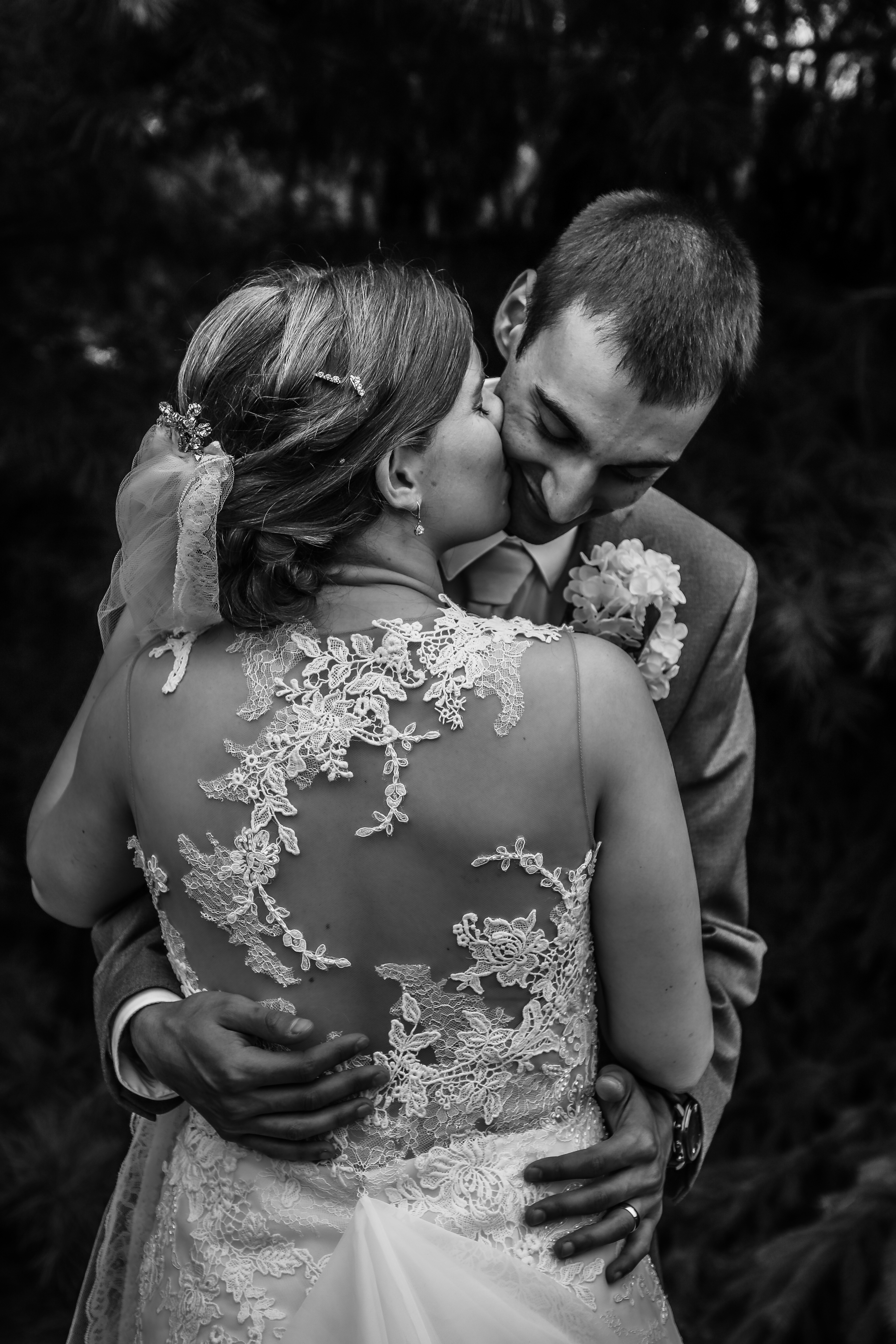black and white portrait of bride kissing groom on cheek
