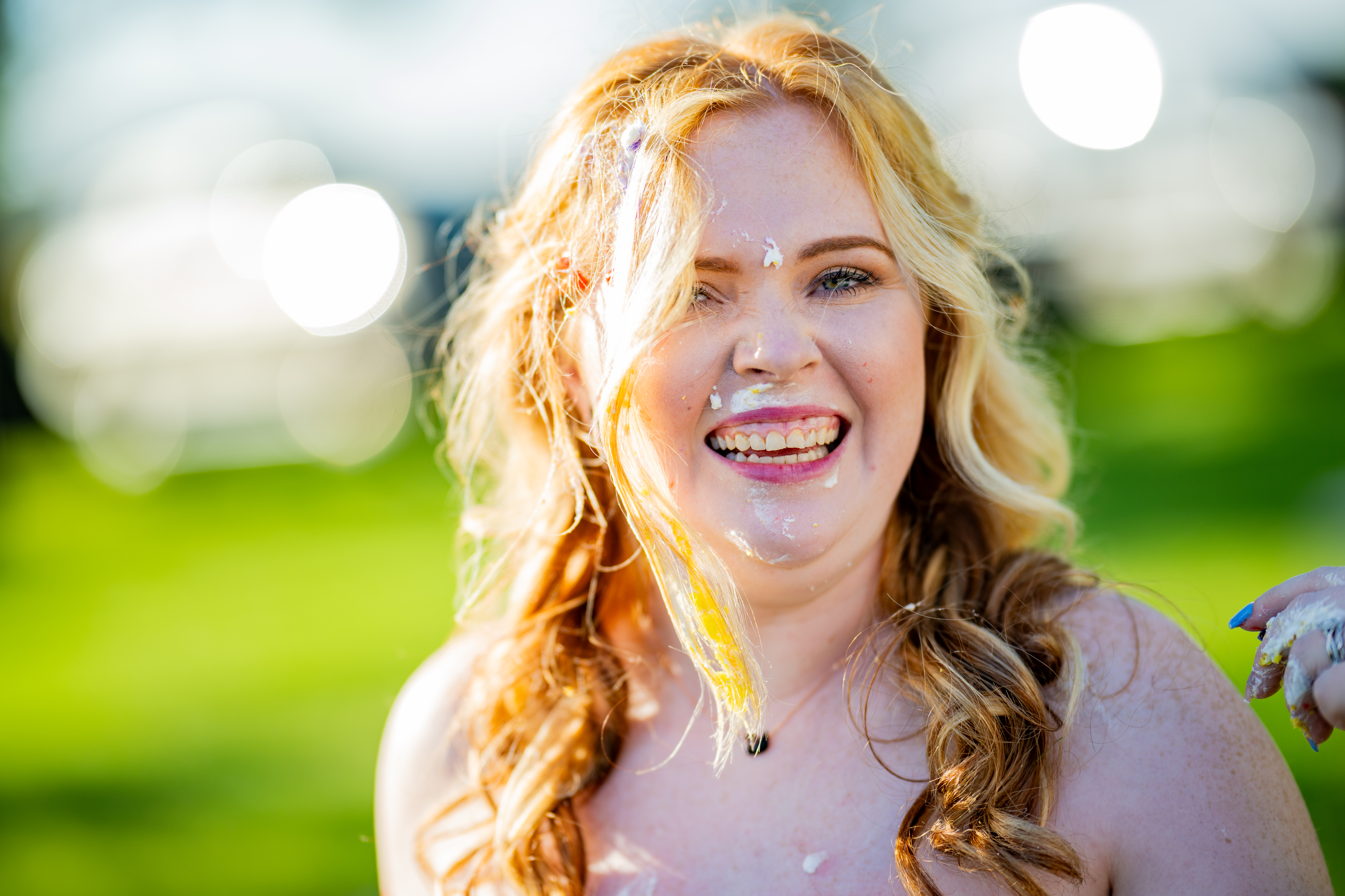 bride smiling with wedding cake on face