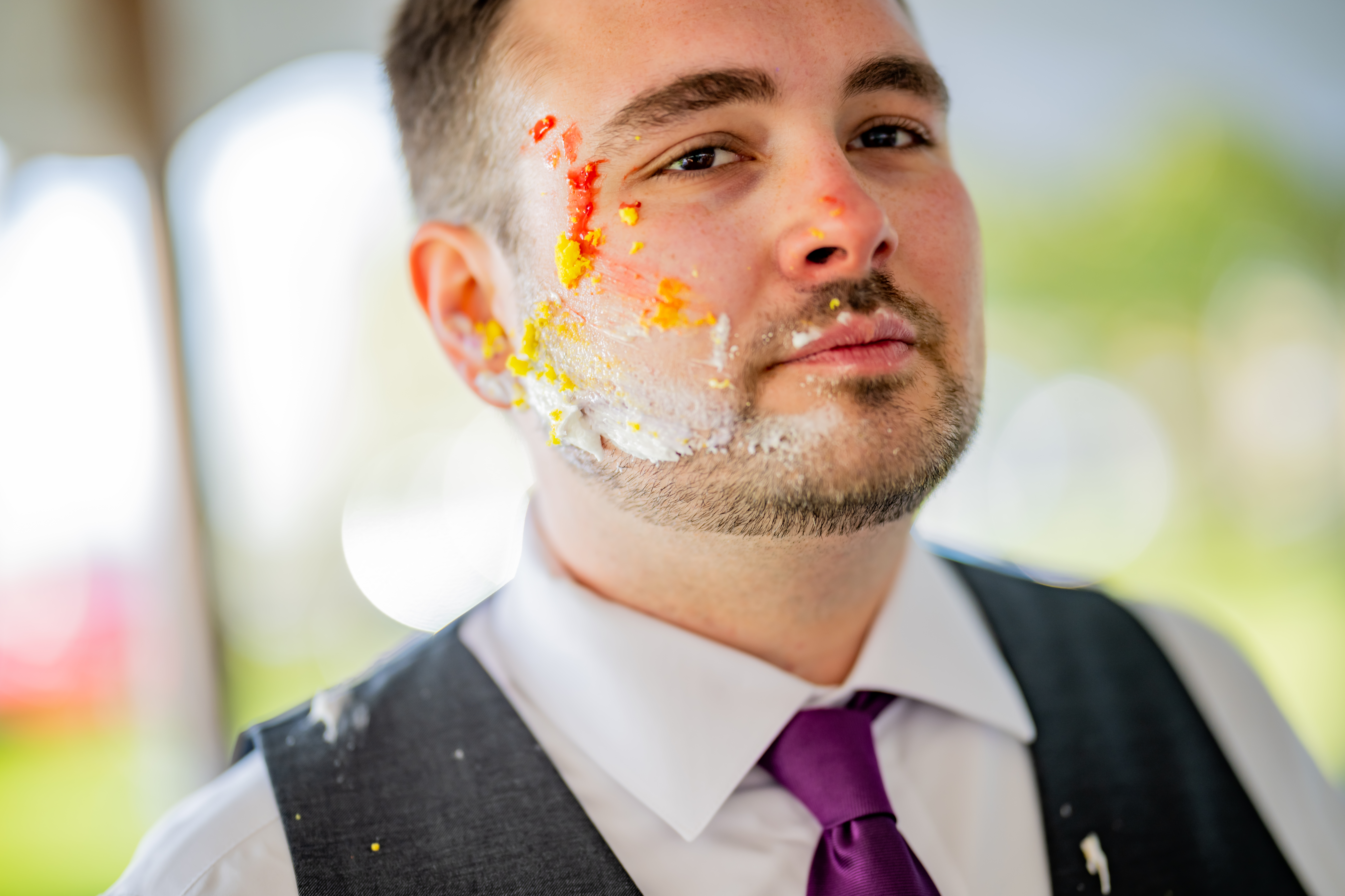 groom with wedding cake on his face